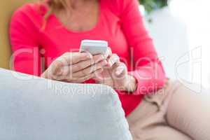 Woman using mobile phone on couch at home