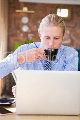 Man having coffee while using laptop