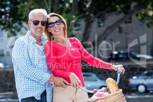 Happy mature couple riding bicycle in city