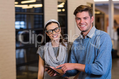 Young colleagues using digital tablet in office