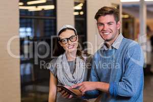 Young colleagues using digital tablet in office