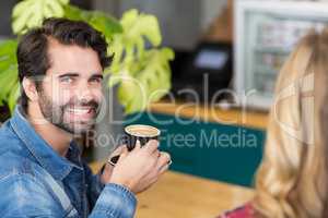 Portrait of happy man drinking cup of coffee in cafe