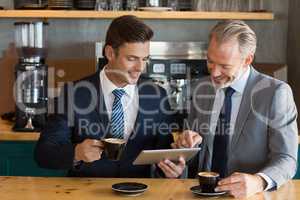 Businessmen using digital tablet in cafÃ©