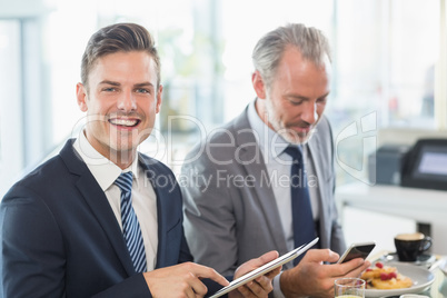 Two businessmen using digital tablet and mobile phone