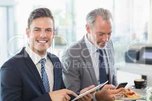 Two businessmen using digital tablet and mobile phone