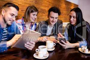 Friends with digital tablet and mobile phone at restaurant