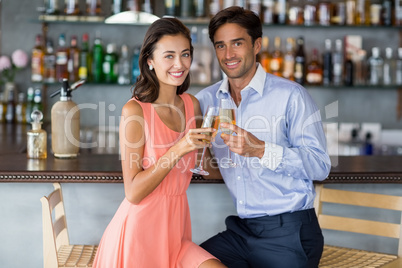 Young couple sitting at bar counter and toasting a glasses of ch