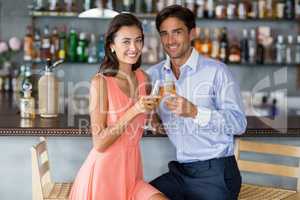 Young couple sitting at bar counter and toasting a glasses of ch