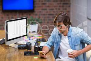 Man with disposable cup using mobile phone in office