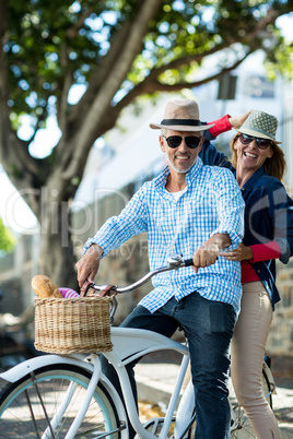 Mature couple riding bicycle by tree