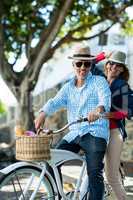 Mature couple riding bicycle by tree