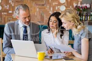Business colleagues discussing on report with laptop on table