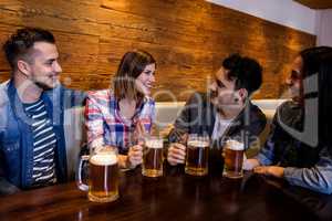 Friends with beer mugs at table in restaurant