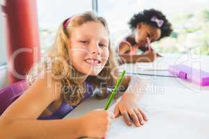 Portrait of girl doing homework in classroom