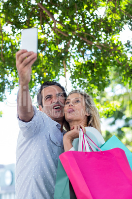 Couple making face while taking selfie in city