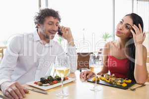 Woman sitting while man talking mobile phone