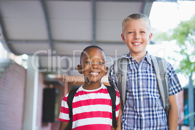 Smiling schoolkids standing in corridor