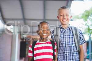 Smiling schoolkids standing in corridor