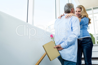 Man hiding rose from woman