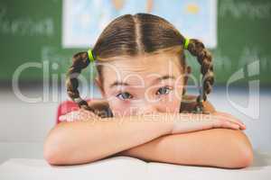 Portrait of schoolgirl leaning on a book in classroom