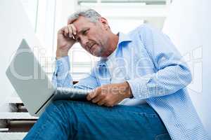 Tensed man using digital tablet on steps