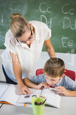 Teacher helping a boy with his homework in classroom