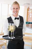 Portrait of waiter holding glasses of champagne