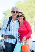 Mature couple holding digital tablet and shopping bags