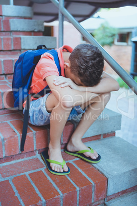 Sad schoolboy sitting alone on staircase