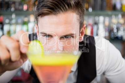 Waiter decorating cocktail with lime