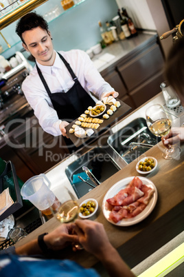 Bartender serving food to customers at counter