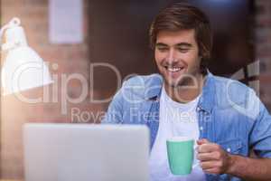 Businessman having coffee while working on laptop