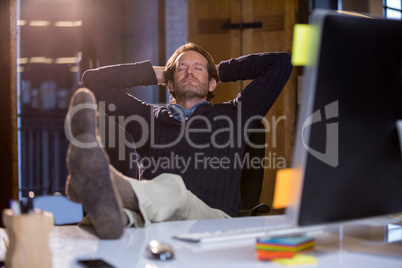 Businessman relaxing on chair at computer desk