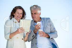 Smiling woman with man using digital tablet