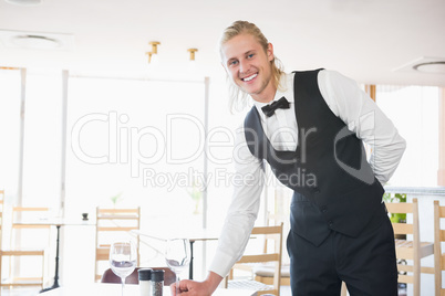 Waiter standing at table with empty glass