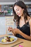 Woman using mobile phone while having meal