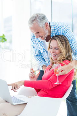 Woman pointing at laptop while having wine