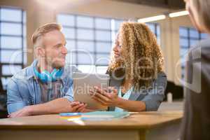 Colleagues smiling while discussing at desk