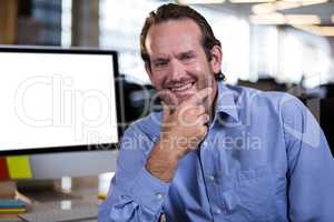 Confident businessman with hand on chin in office