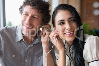 Couple listening to music together in cafeteria