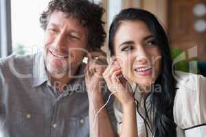 Couple listening to music together in cafeteria