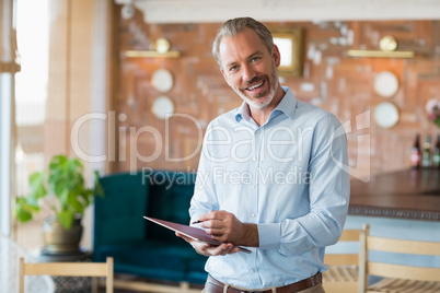 Portrait of smiling man writing in a file