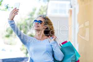 Woman taking selfie while carrying shopping bags