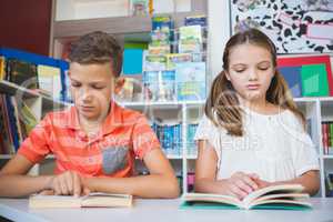 Schoolkids reading book in library