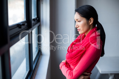 Thoughtful woman standing by window in office