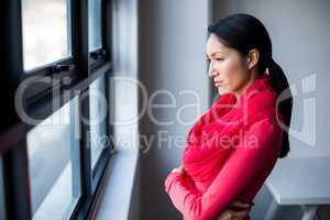 Thoughtful woman standing by window in office