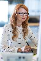 Businesswoman using graphics tablet at desk in office