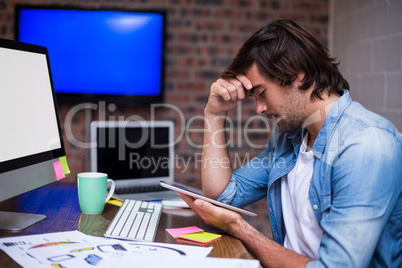 Stressed businessman holding digital tablet