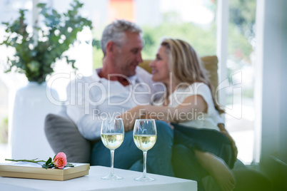 Romantic couple sitting on armchair with white wine and gift box