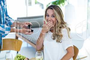 Surprised woman receiving ring by table